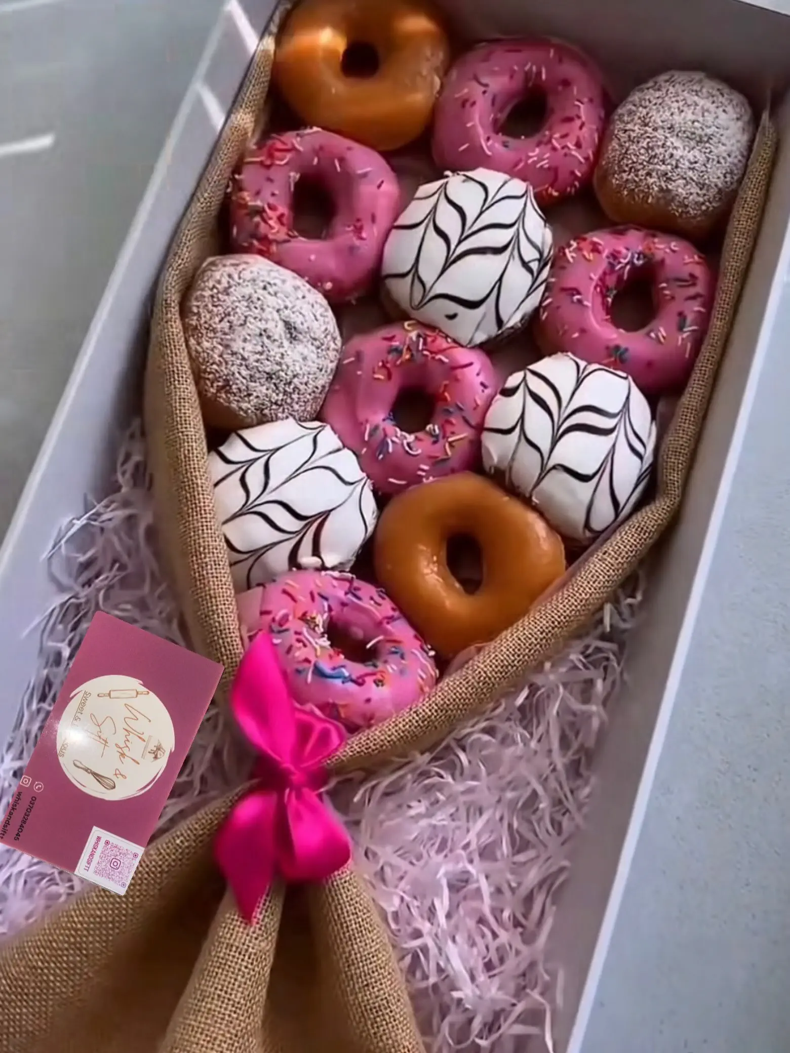 Assorted donut bouquet with pink sprinkled, chocolate swirled and glazed donuts in a gift style arrangement
